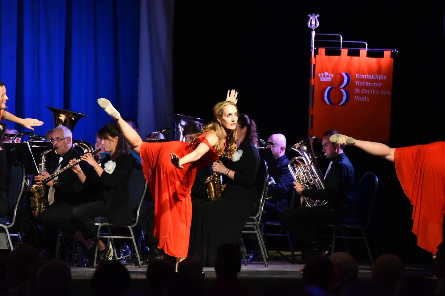 Danseressen in rode jurken voor het spelende harmonieorkest